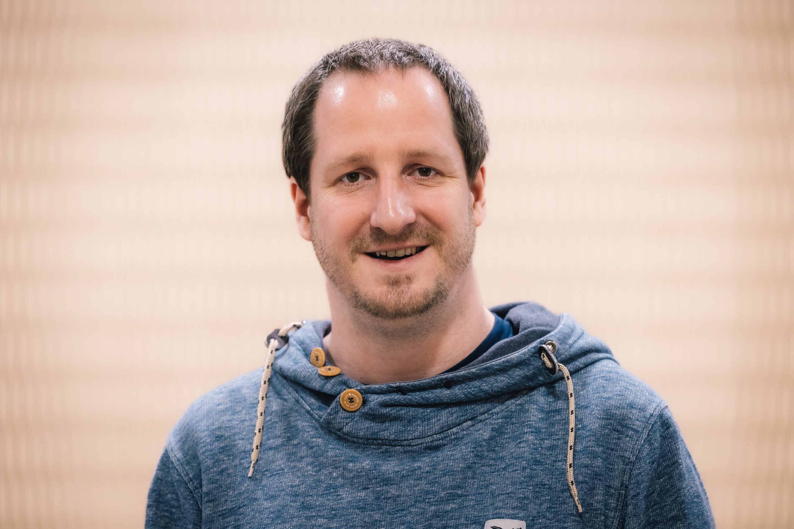 Porträt von einem Mann in einem blauen Pullover.