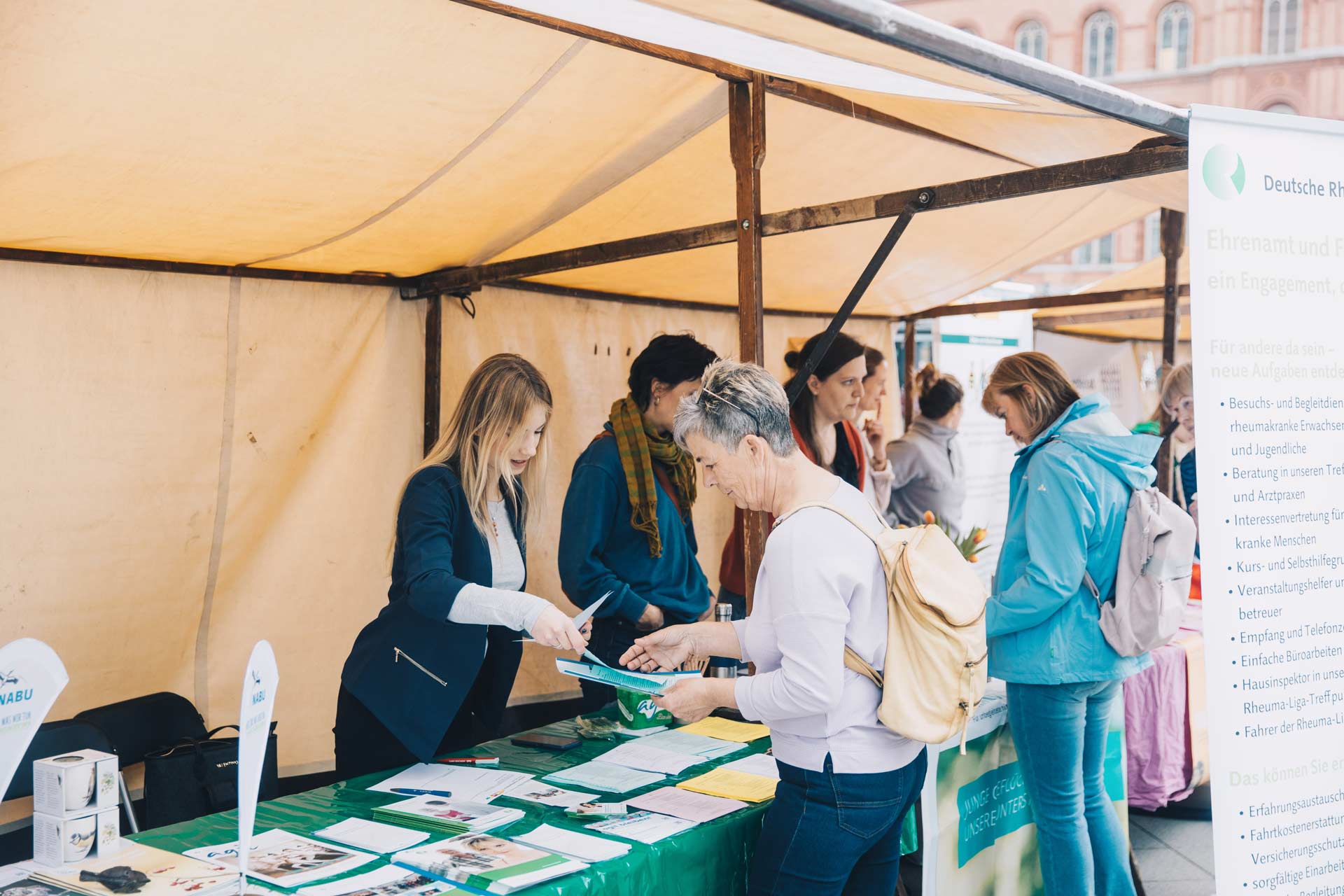 Ein Informationsstand auf der Berliner Freiwilligenbörse. Eine Frau informiert sich am Stand über das Angebot und nimmt Flyer mit.